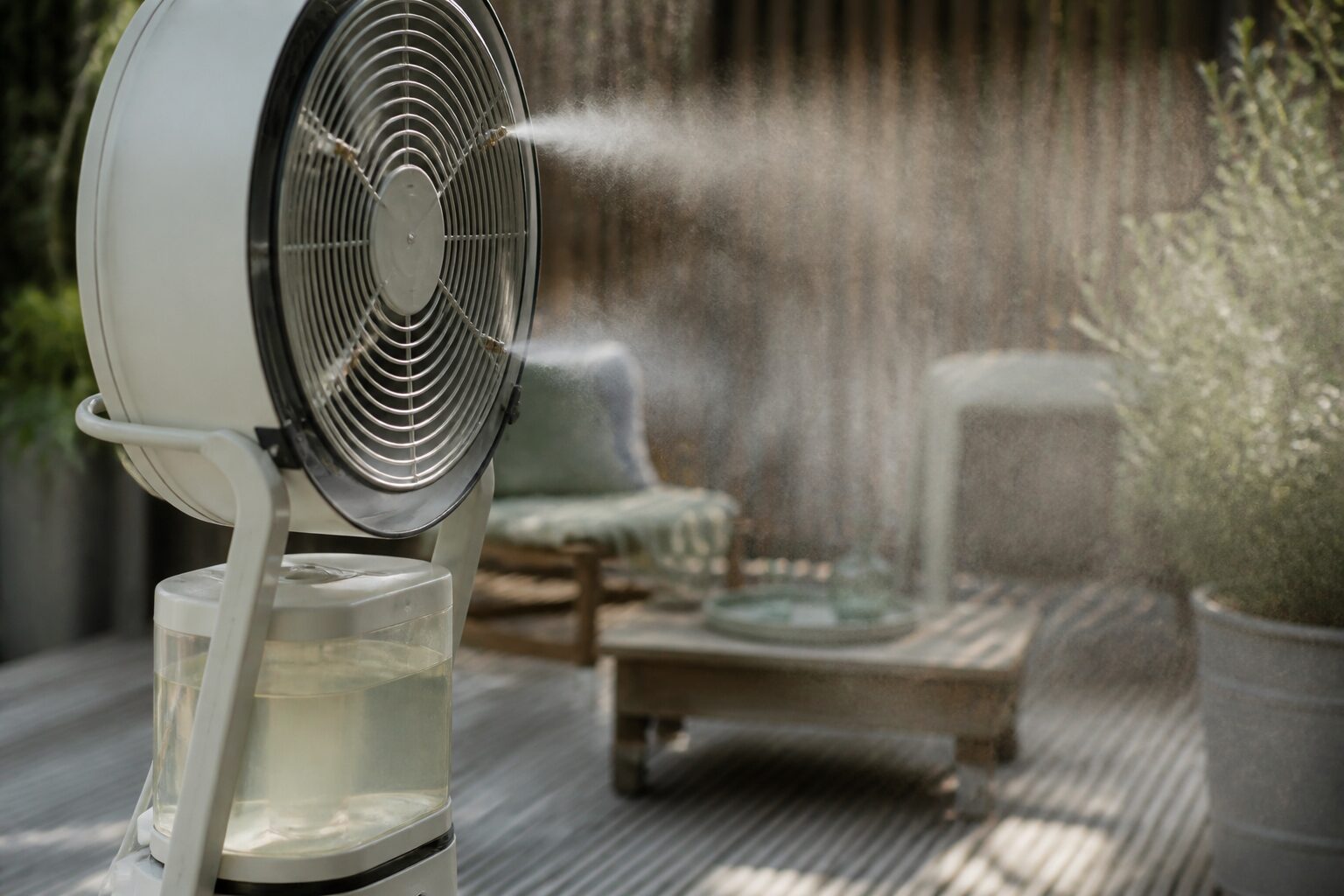 Brumisateur de terrasse sur pied à roulettes diffusant une brume rafraîchissante sur une terrasse en bois
