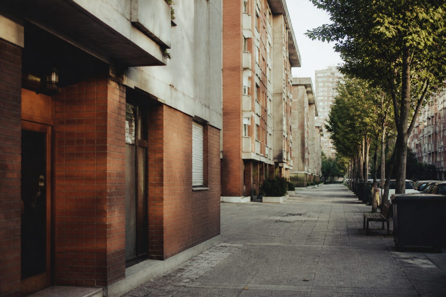Vue d'une rue de quartier populaire à Nanterre, immeubles de brique et béton années 1970, lumière naturelle douce
