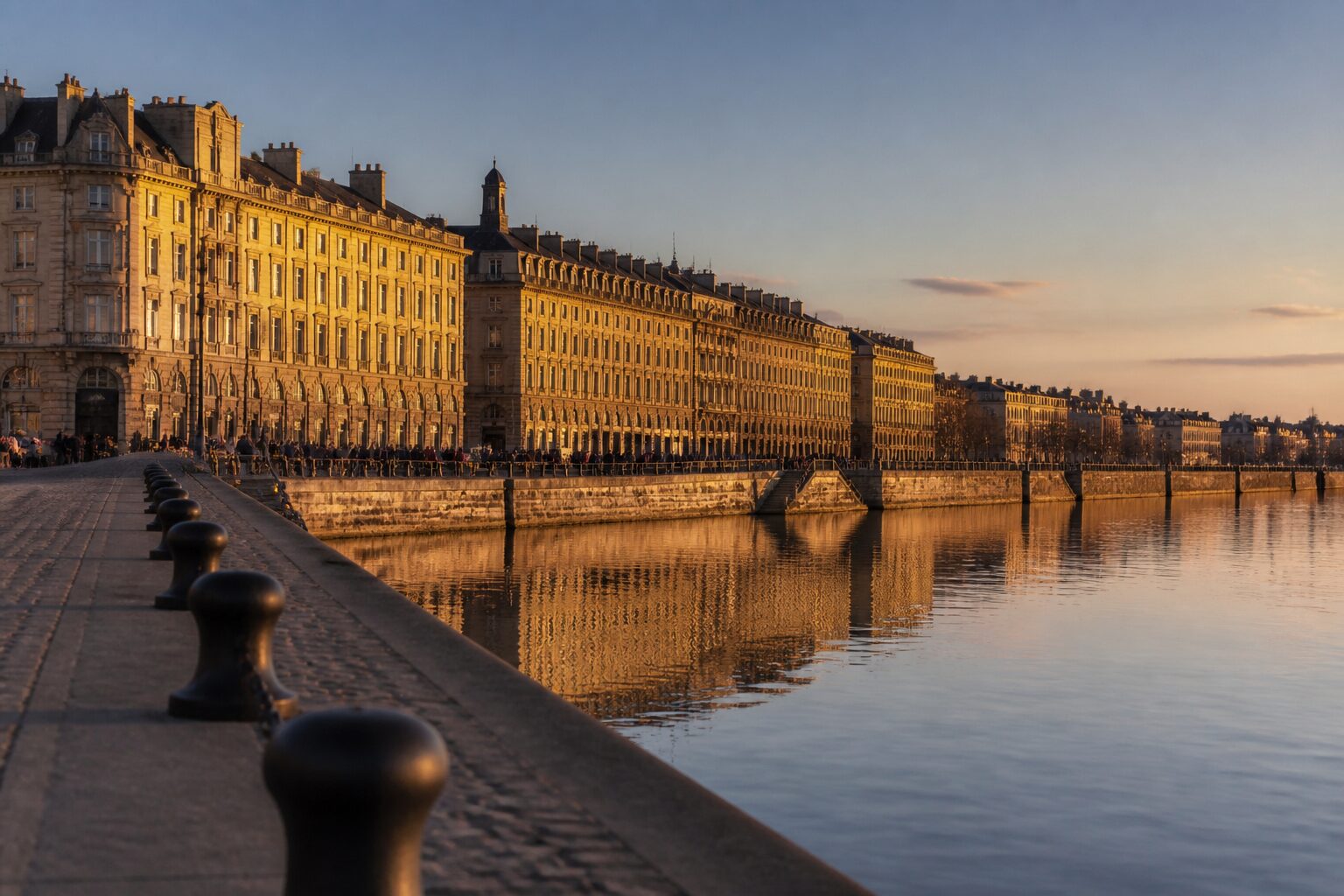 Perspective sur les quais de Bordeaux en lumière dorée, immeubles haussmanniens reflétés sur la Garonne, ambiance sereine