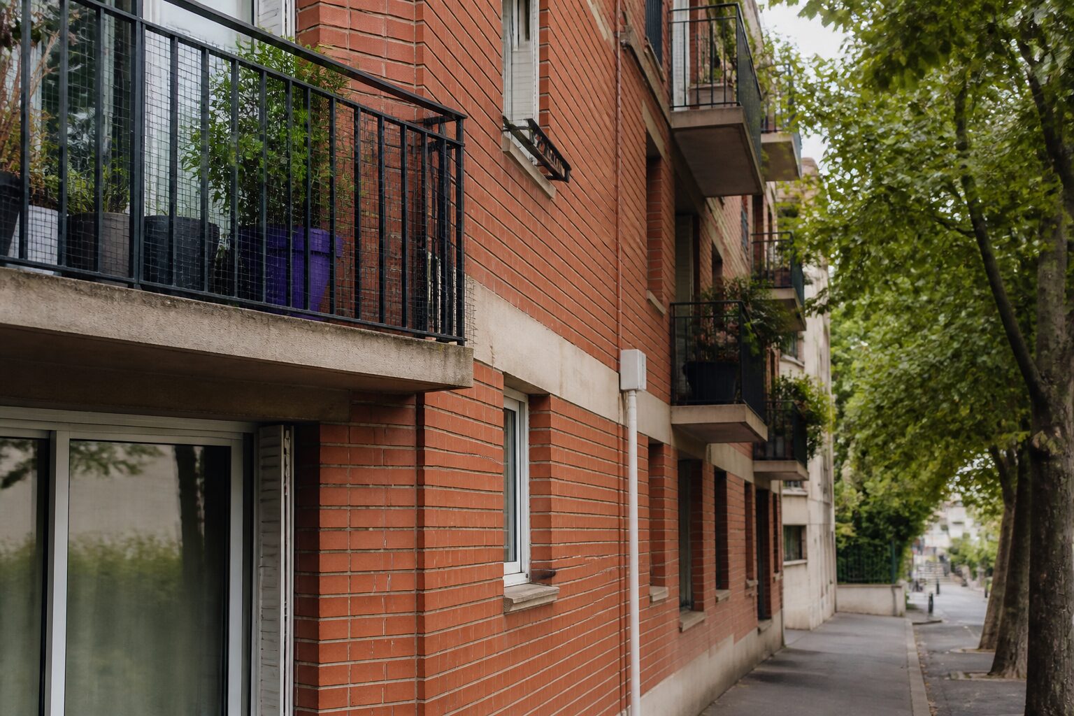 Vue de rue d'un quartier résidentiel de Corbeil-Essonnes, immeubles de brique et façades années 70, lumière naturelle douce