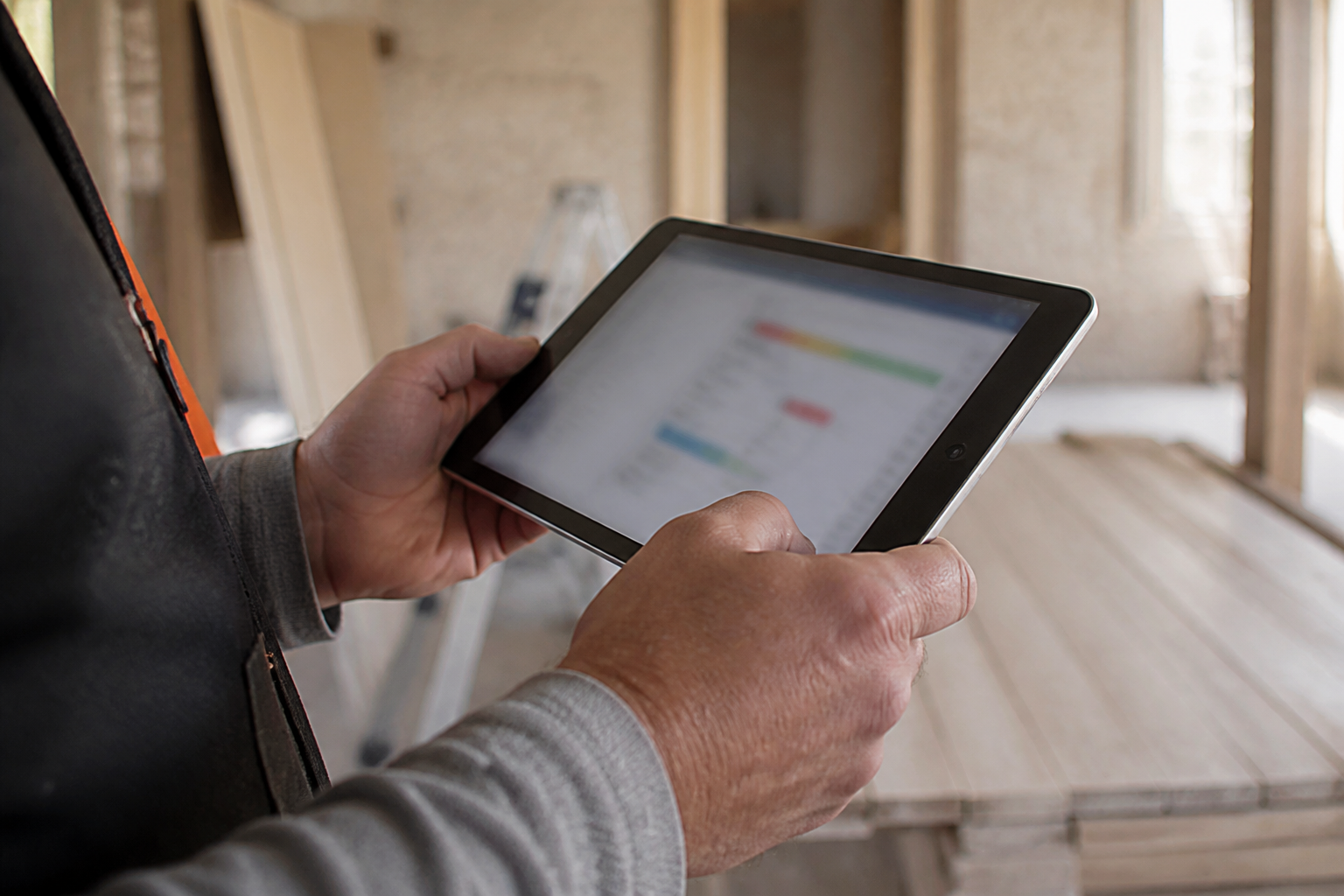Artisan tenant une tablette de suivi de chantier sur un logiciel de gestion BTP